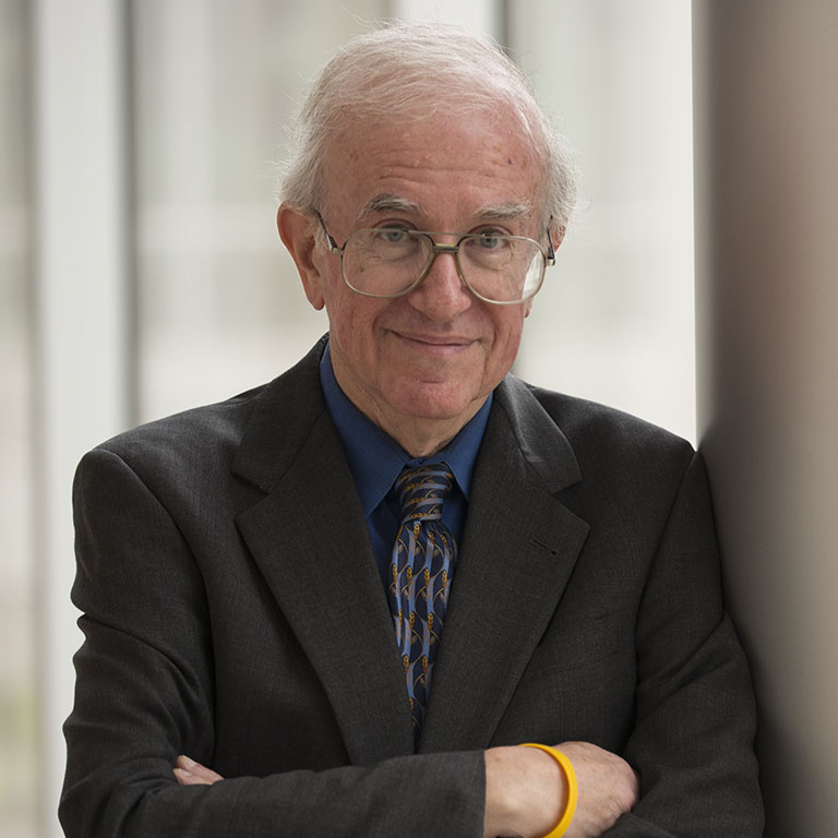 Dr Einhorn leaning against a wall with arms folded.