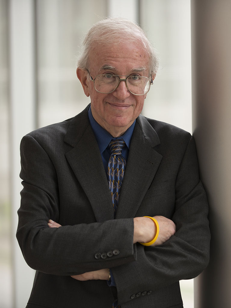 Dr Einhorn leaning against a wall with arms folded.